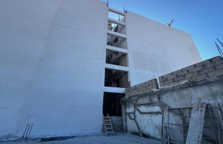 The application of stucco on the right side facade is completed